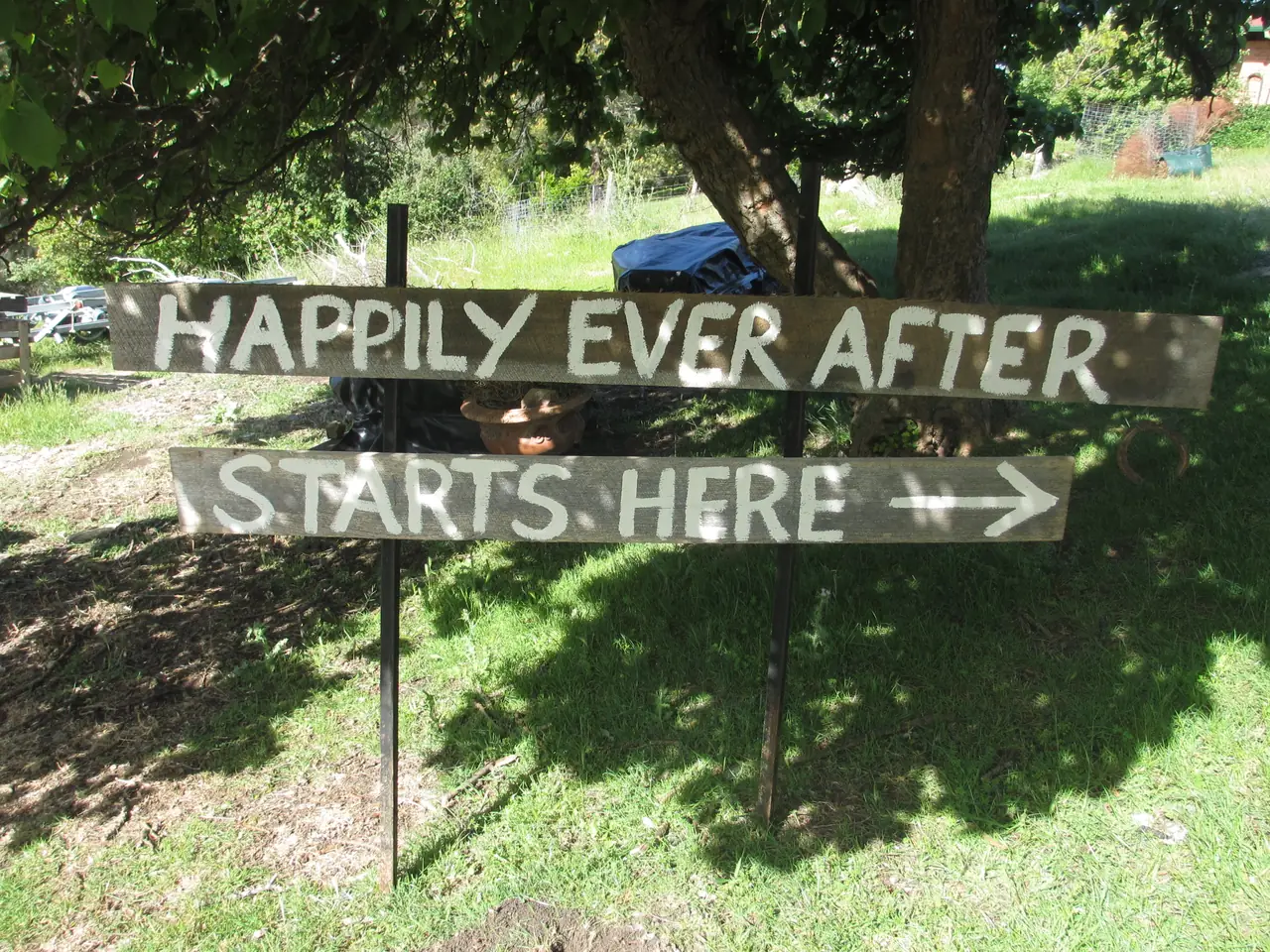 A timber sign in a garden reads Happily ever after starts here.